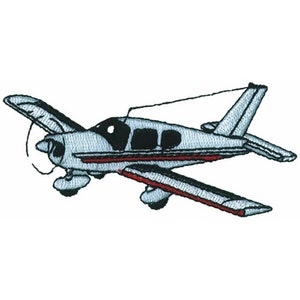 Può includere: Un aereo monomotore grigio e bianco con finiture rosse. L'aereo è in volo e ha un'elica nella parte anteriore.