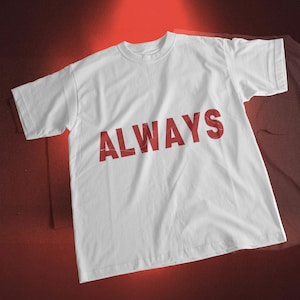 May include: White t-shirt with the word "ALWAYS" printed in red across the front. The shirt has short sleeves and a crew neck. The text has a slightly distressed appearance.