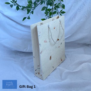 May include: A white gift bag with a brown paper texture and a rope handle. The bag has a speckled pattern of orange and brown flecks. The bag is labeled "Gift Bag 1".