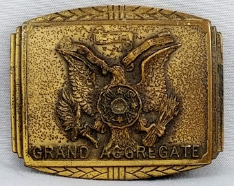 May include: A gold-toned belt buckle with an eagle design and the words "Grand Aggregate" on the bottom.