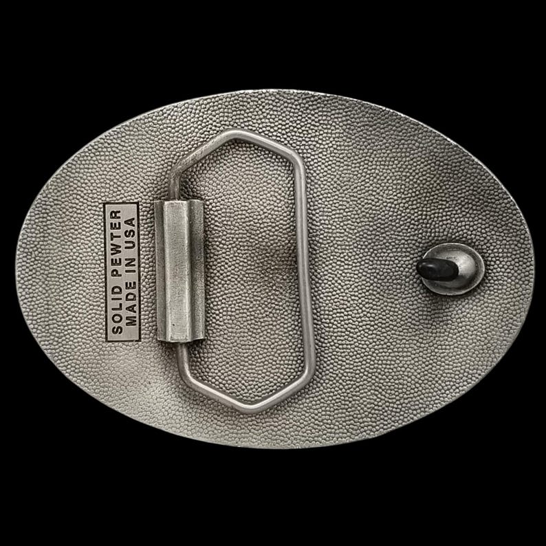 May include: Oval-shaped, solid pewter belt buckle with a textured surface. The buckle features a rectangular bar and a metal loop for the belt. The text "SOLID PEWTER MADE IN USA" is stamped on the buckle.