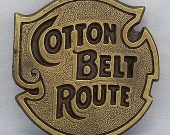 May include: A brass belt buckle with the words "Cotton Belt Route" embossed in black lettering.
