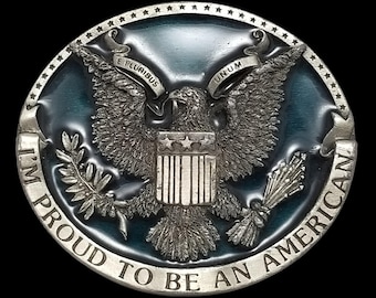 May include: A circular belt buckle in silver, featuring a detailed depiction of an American eagle. The buckle has a blue enamel background and the text "I'M PROUD TO BE AN AMERICAN".