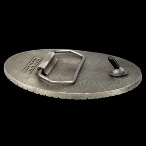 May include: Oval-shaped, solid pewter belt buckle with a textured surface. Features a metal loop and a black post. The text "SOLID PEWTER MADE IN USA" is visible. The buckle is designed for use with a belt.
