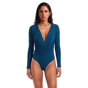 Può includere: Body color teal con maniche lunghe e scollatura a V profonda. Il tessuto drappeggia sul petto, creando una silhouette lusinghiera. Il capo intero è aderente e adatto a varie occasioni.