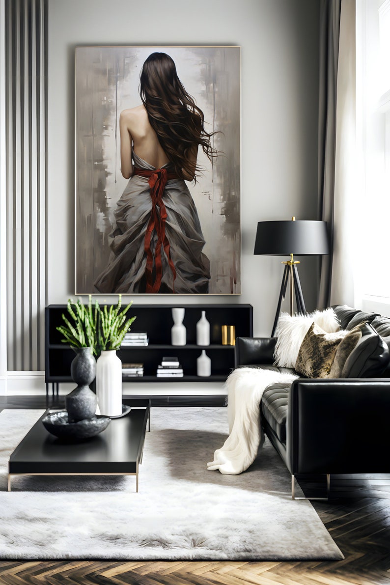 May include: A painting of a woman in a flowing grey dress with a red ribbon tied around her waist. The woman is standing with her back to the viewer and her long brown hair is flowing in the wind. The painting is set against a background of muted grey and brown tones.
