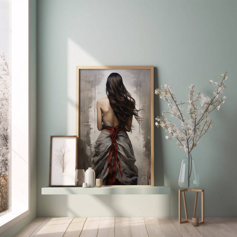May include: A framed painting of a woman with long brown hair wearing a flowing grey dress with a red ribbon tied around her waist. The painting is hanging on a light green wall with a white shelf below it.