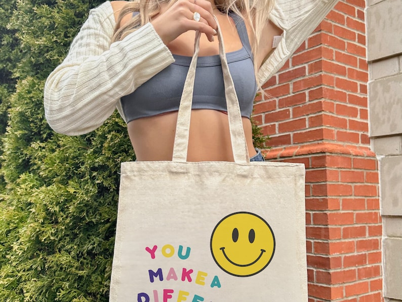 May include: A white canvas tote bag with the text "YOU MAKE A DIFF" in colorful letters and a yellow smiley face.