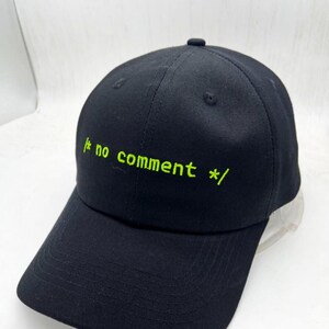 May include: A black baseball cap with a green embroidered design that says "/* no comment */".