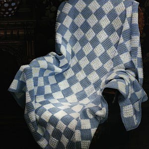 May include: A blue and white checked crochet throw blanket draped over a chair. The blanket is made with a simple stitch pattern and has a soft, cosy texture.