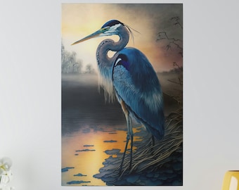 May include: A canvas print featuring a blue heron standing near a body of water at sunset. The bird has long legs and a long beak. The water reflects the orange and yellow hues of the setting sun. The background includes trees and a misty sky.