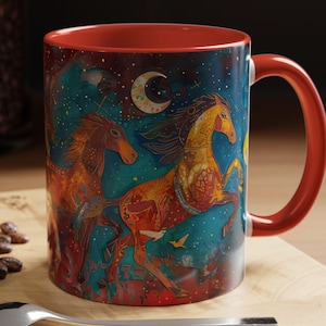 May include: A red ceramic mug with a colorful design of three horses running under a crescent moon and stars. The horses are painted in shades of orange, yellow, and brown, with intricate details. The background is a dark blue with a starry sky effect.