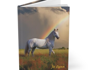 May include: A white horse stands in a field with a rainbow in the sky. The horse has a white mane and tail. The field is green with wildflowers. The sky is cloudy and blue. The text "Jo Lynn" is printed at the bottom of the image.