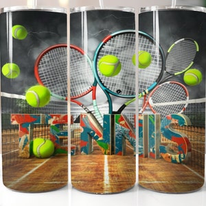 May include: A stainless steel tumbler featuring a tennis theme. The design includes tennis rackets, tennis balls, and the word "TENNIS" in a 3D font. The background shows a tennis court and a stormy sky.