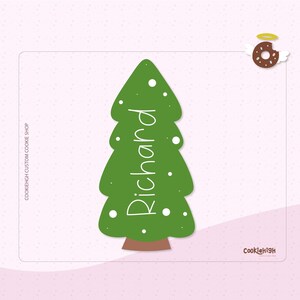 Puede incluir: Un diseño verde en forma de árbol de Navidad con el nombre "Richard" en escritura blanca. El árbol tiene puntos blancos y un tronco marrón. Una rosquilla con alas y un halo está en la esquina superior derecha.