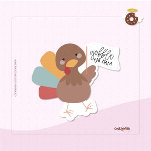May include: A cartoon turkey sticker with a brown body, a yellow beak, and a red wattle. The turkey holds a white flag that reads "gobble eat ham". The turkey has colorful tail feathers and is set against a pink background.
