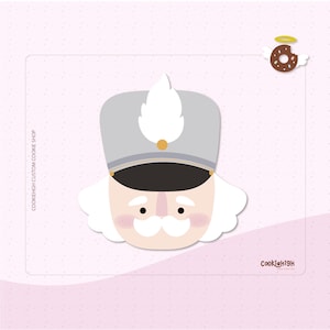 Op de afbeelding: Een cartoon illustratie van het gezicht van een notenkraker soldaat, met een grijze hoed, witte pluim en gouden accenten. Het gezicht heeft een witte snor en roze wangen. De achtergrond is lichtroze met de tekst "COOKIEHGH CUSTOM COOKIE SHOP".