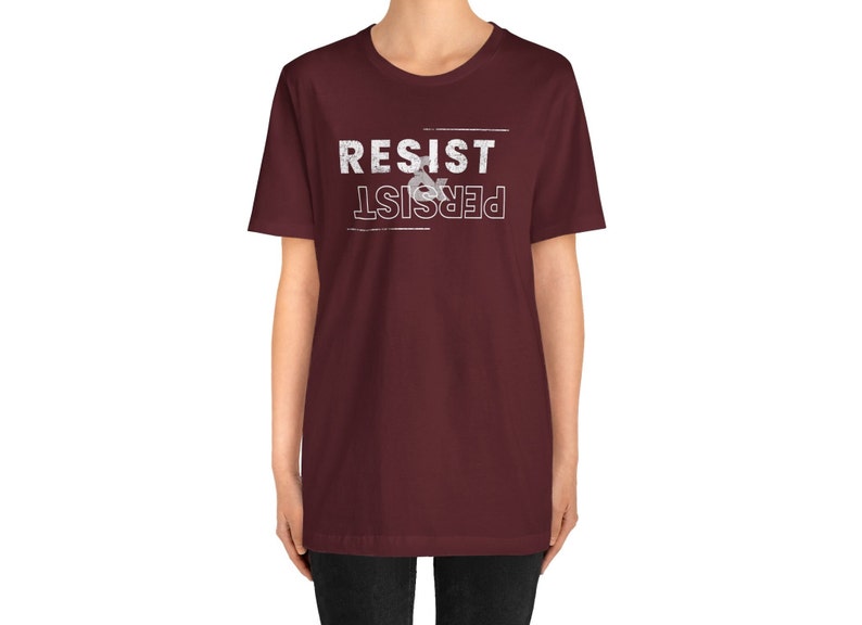 May include: A maroon t-shirt with white text that reads "Resist & Persist" in a distressed font.