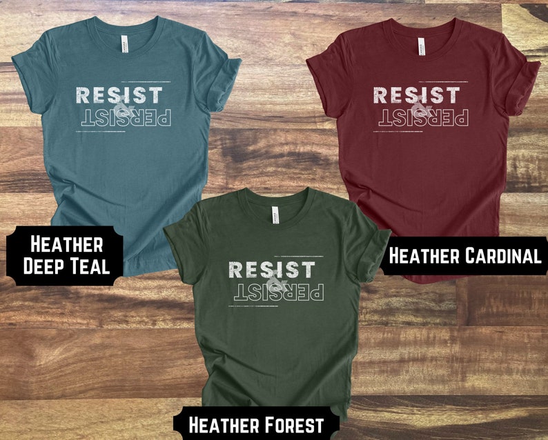 May include: Three t-shirts in different colors with the text "Resist & Persist" printed on the front. The colors are heather deep teal, heather cardinal, and heather forest.