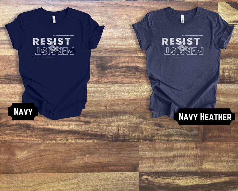 May include: Two t-shirts with the text "Resist & Persist" in white lettering on a navy blue and navy heather background.