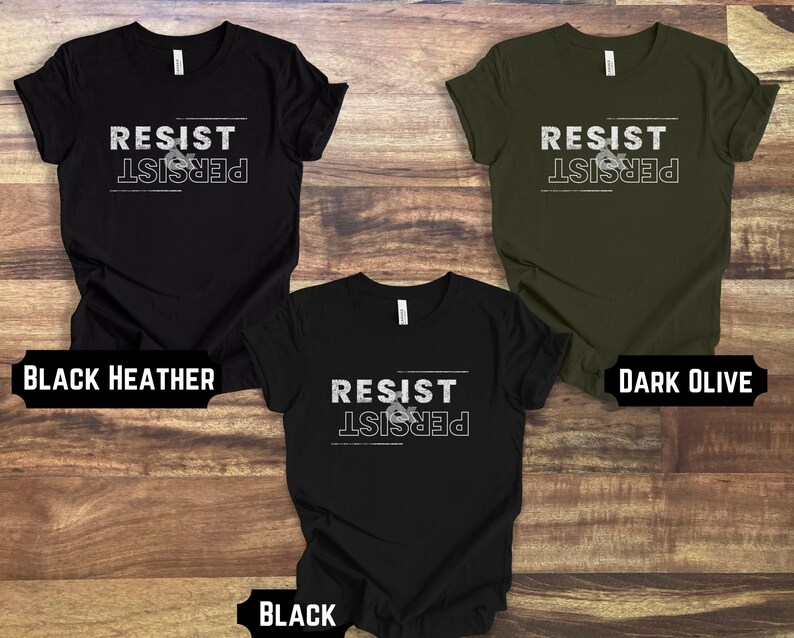 May include: Three t-shirts with the text "Resist & Persist" in white on a black, dark olive, and black heather background.