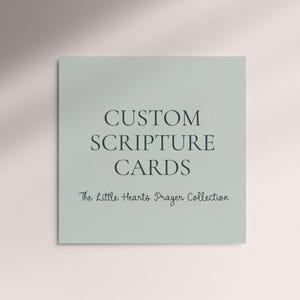 May include: A square, light green card with the text "CUSTOM SCRIPTURE CARDS" in a serif font. Below, in a script font, is "The Little Hearts Prayer Collection". The card is centered on a white background with soft shadows.