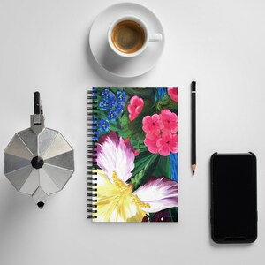 May include: A spiral bound notebook with a colorful floral design. The cover features pink, yellow, blue, and green flowers on a dark green background.