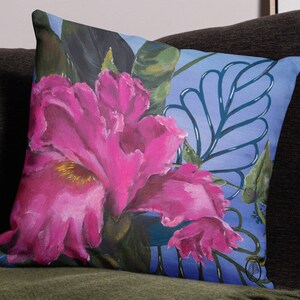 May include: A throw pillow with a floral design featuring a large pink flower with a yellow center, surrounded by green leaves and a blue background with a stylized leaf pattern.
