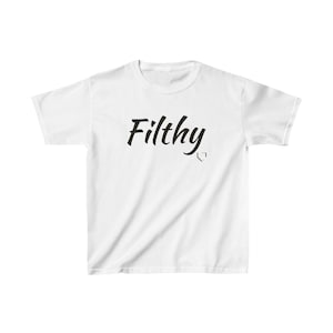 Könnte beinhalten: Weißes T-Shirt mit dem Wort "Filthy" in schwarzer Schrift und einer kleinen Baseball-Homeplate-Grafik. Das Shirt hat kurze Ärmel, einen Rundhalsausschnitt und ist aus weichem Material.