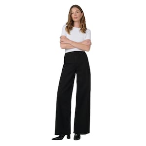 May include: Black wide-leg pants with a high waist. The pants are paired with a white short-sleeve top. The model is standing with arms crossed.