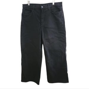 May include: Black, high-waisted, wide-leg pants hanging on a white background. The pants have a button and zipper closure, front pockets, and belt loops. The fabric appears to be a sturdy cotton or blend, suitable for casual wear.