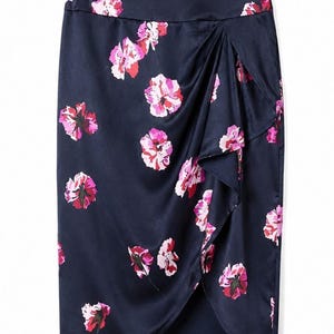 May include: A navy blue pencil skirt with a floral pattern. The skirt features a wrap design with a ruffled edge. The flowers are pink and red, and the skirt is made of a shiny fabric.
