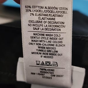 May include: A white clothing tag with black text detailing fabric composition: 63% cotton, 35% lyocell, and 2% elastane. Washing instructions include machine wash cold, gentle cycle, and tumble dry low. The tag also includes a product code and date.