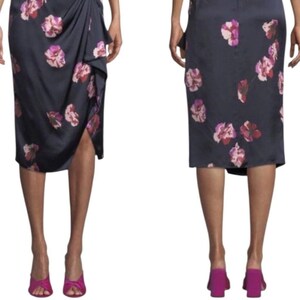 May include: A navy blue skirt with a floral pattern in shades of pink and red. The skirt has a draped design on the front and a slit. The model is wearing pink heels.