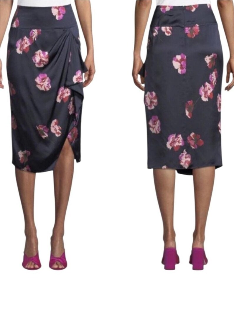 May include: A navy blue skirt with a floral pattern in shades of pink and red. The skirt has a draped design on the front and a slit. The model is wearing pink heels.