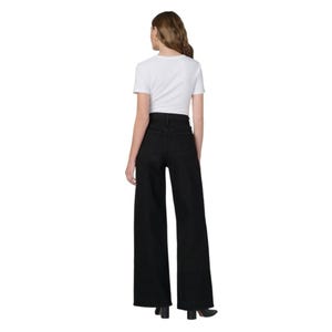May include: A person wearing a white, short-sleeved t-shirt and black wide-leg pants. The pants have a high waist and a long, flowing silhouette. The outfit is simple and modern, with a focus on the pants' shape.