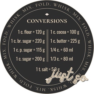 May include: A black and white circle with the text "CONVERSIONS" in the center. The circle contains a chart with measurements for common baking ingredients, such as flour, sugar, and butter, in both cups and grams. The text "Just So" is written in a stylized font at the bottom of the circle.