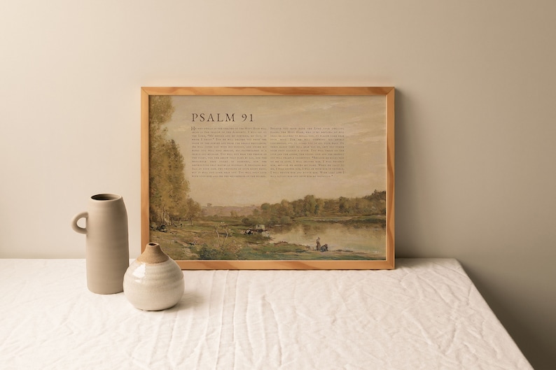 May include: A framed print of Psalm 91 with a watercolor painting of a river scene. The text is in brown font on a beige background. The painting depicts a river with trees on either side and a few figures in the distance.