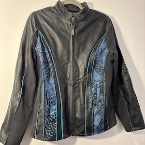 May include: Black leather jacket with blue patterned panels and teal stitching. The jacket has a zip-up front and a stand-up collar. The sleeves are a dark gray denim material.