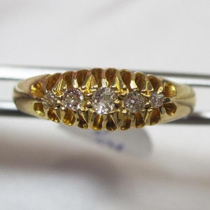 May include: A gold band ring with five small diamonds set in a row.