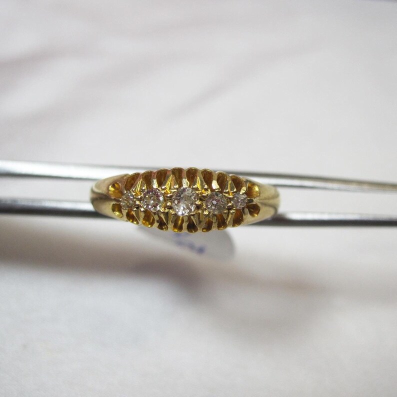 May include: A gold band ring with five small diamonds set in a row.