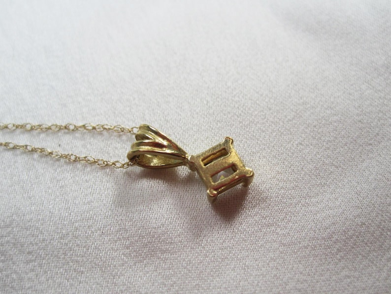 May include: A gold chain necklace with a pendant shaped like the Roman numeral 'II'. The pendant has a simple design with a smooth finish.