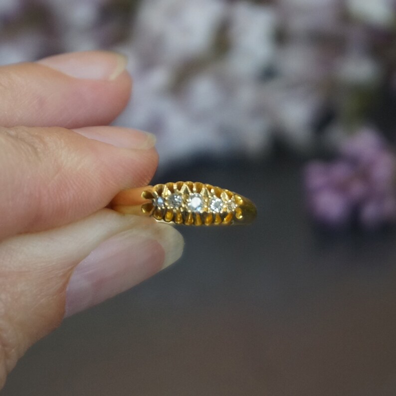 May include: A gold band ring with five small diamonds set in a row.