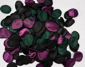 May include: A collection of numerous small, rounded fabric petals in shades of deep forest green, dark purple, and solid black. Each petal has a smooth, slightly reflective satin-like finish, creating a layered and textured appearance.