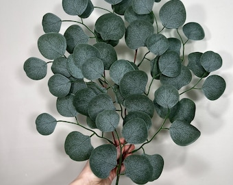 Op de afbeelding: Een tak van kunstmatige eucalyptus met groene bladeren. De bladeren hebben een getextureerde, gegroefde uitstraling.