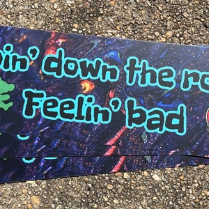 May include: Three stickers with a space-themed background. The stickers feature a green creature, the text "Goin' down the road Feelin' bad", and a red, white, and blue skull with a lightning bolt.