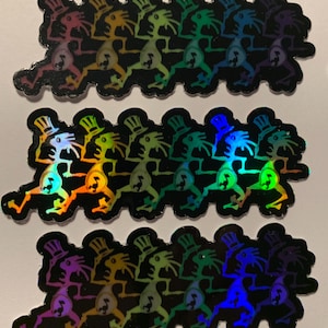 May include: Holographic stickers featuring a repeating pattern of whimsical figures in top hats, each in a different color. The figures are running, with a stylized design. The stickers have a black border and a reflective, rainbow sheen.