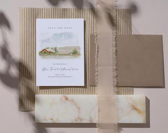 May include: A wedding invitation suite featuring a watercolor illustration of a lakeside venue. The invitation card reads "Save the Date" and includes the names of the couple and the wedding date. The suite includes an envelope, a ribbon, and a decorative stone.