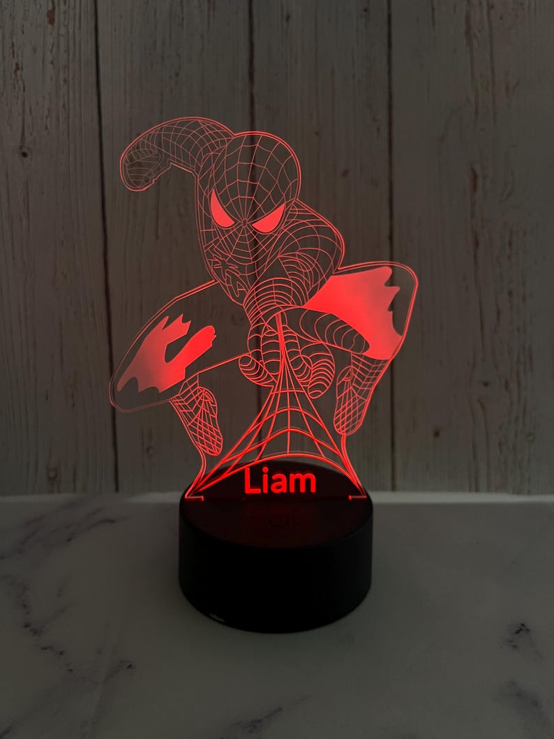 May include: Red 3D printed night light featuring a Spiderman design with a web and the name "Liam" printed below.