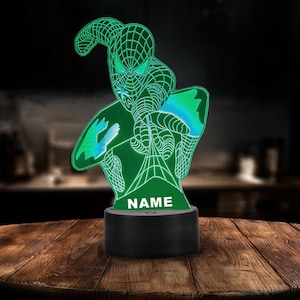 May include: A green and blue 3D printed night light shaped like a superhero with the word "NAME" printed on the base.